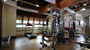 Un gimnasio con cintas de correr, máquinas de pesas y un espejo grande.