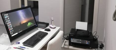 A modern office space with a desk, laptop, keyboard, mouse, and printer.