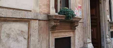A historic building facade with a plaque, arched windows, and a door.