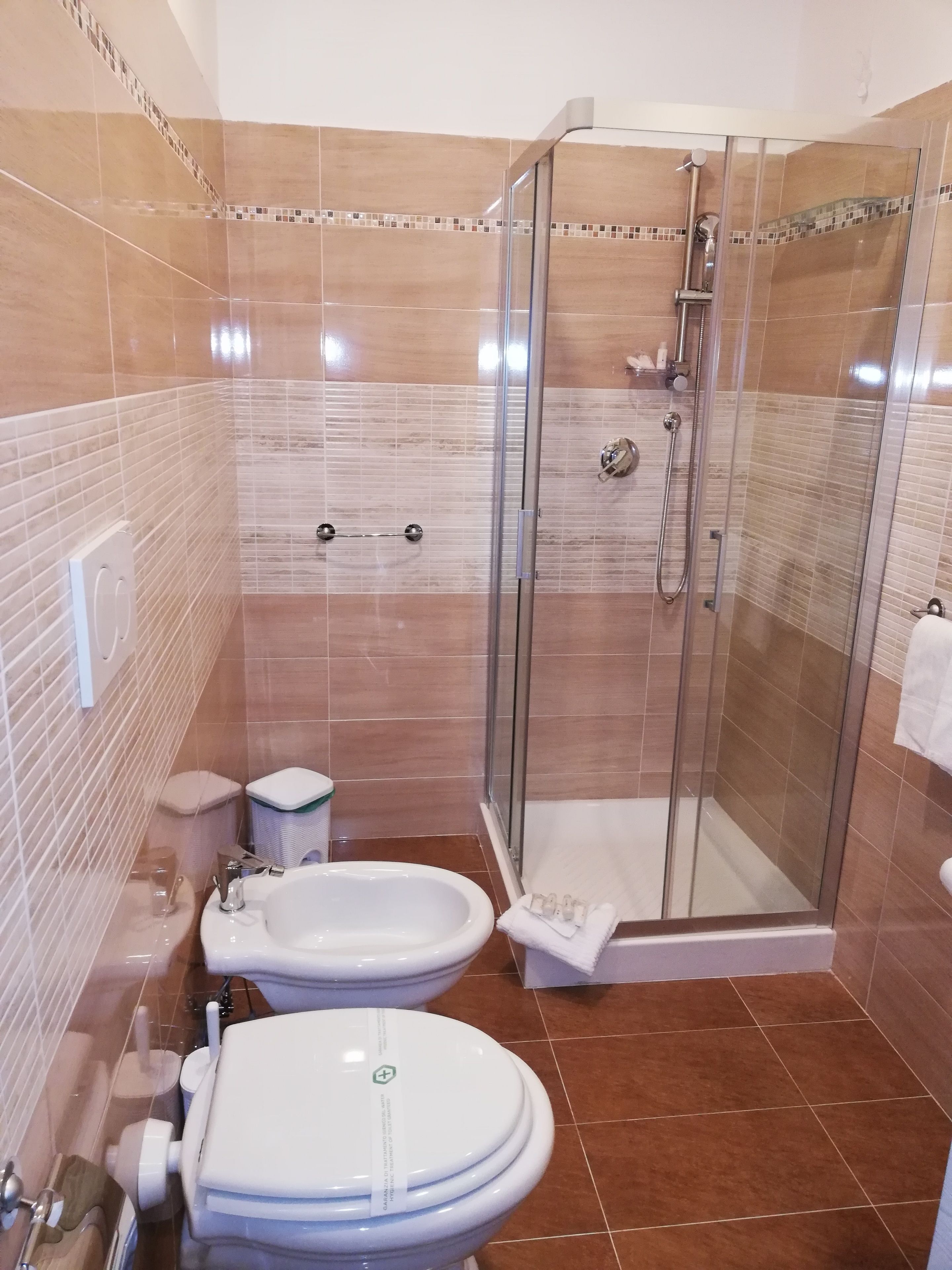 Un bagno moderno con doccia vetrata, un water e due lavandini.