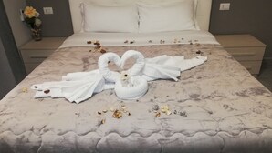 Un lit décoré de serviettes pliées en forme de cygnes et parsemé de pétales de fleurs.