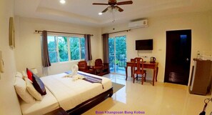 Habitación de hotel con cama, escritorio, silla, televisor y puerta.