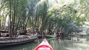 A river with boats and a red canoe in the foreground. - Baan Klangsuan Bang Korbua (Phra Pradaeng)