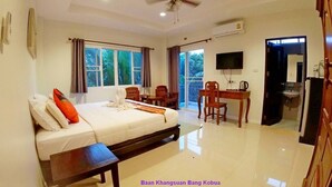 A hotel room with a bed, a desk, a chair, a television, and a bathroom visible through an open door. - Baan Klangsuan Bang Korbua (Phra Pradaeng)