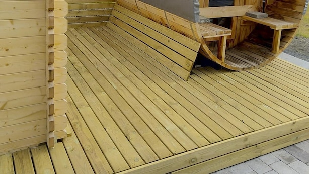 A wooden sauna with a curved roof and a wooden deck.