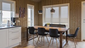 A modern kitchen with wooden walls, a large window, and a dining area with a wooden table and black chairs.