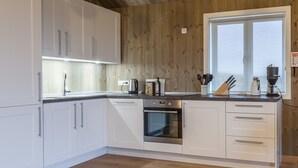 A modern kitchen with white cabinets, a built-in oven, and a window with a view.