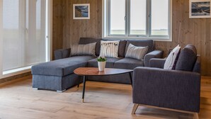 A modern living room with a sectional sofa, a round coffee table, and a small side table.