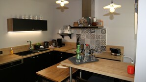 A modern kitchen with a black countertop, wooden cabinets, a built-in oven, and a backsplash with patterned tiles. - Villa Victoire - Charming house with garden - 10 people - 5 bedrooms - 3 bathrooms - 2 WCs (Aulos)