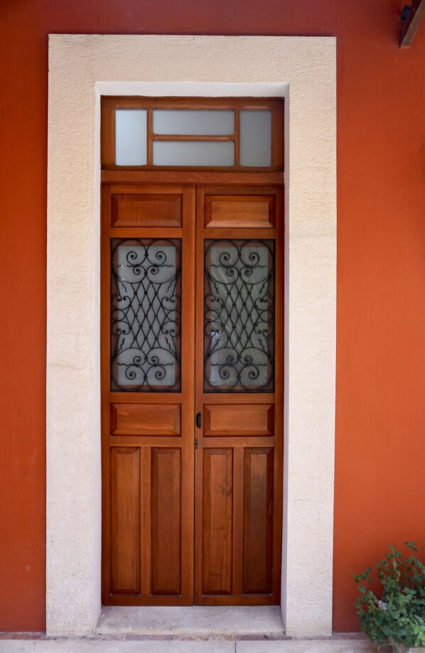 A wooden double door with glass panels and decorative metalwork. - Style and luxury in the heart of El Centro (Merida)