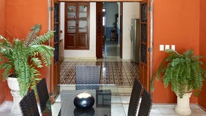 A dining area with a glass table and chairs, a ceiling fan, and a view into the kitchen through an archway. - Style and luxury in the heart of El Centro (Merida)