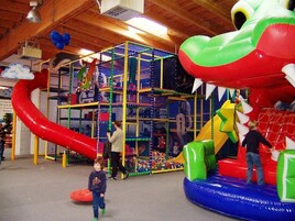 Zona de juegos con estructura de escalada, toboganes y juegos hinchables.