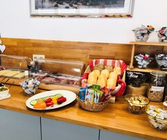 Un bufé de desayuno con diferentes opciones de comida, como pan, pasteles y una bandeja de vegetales cortados.