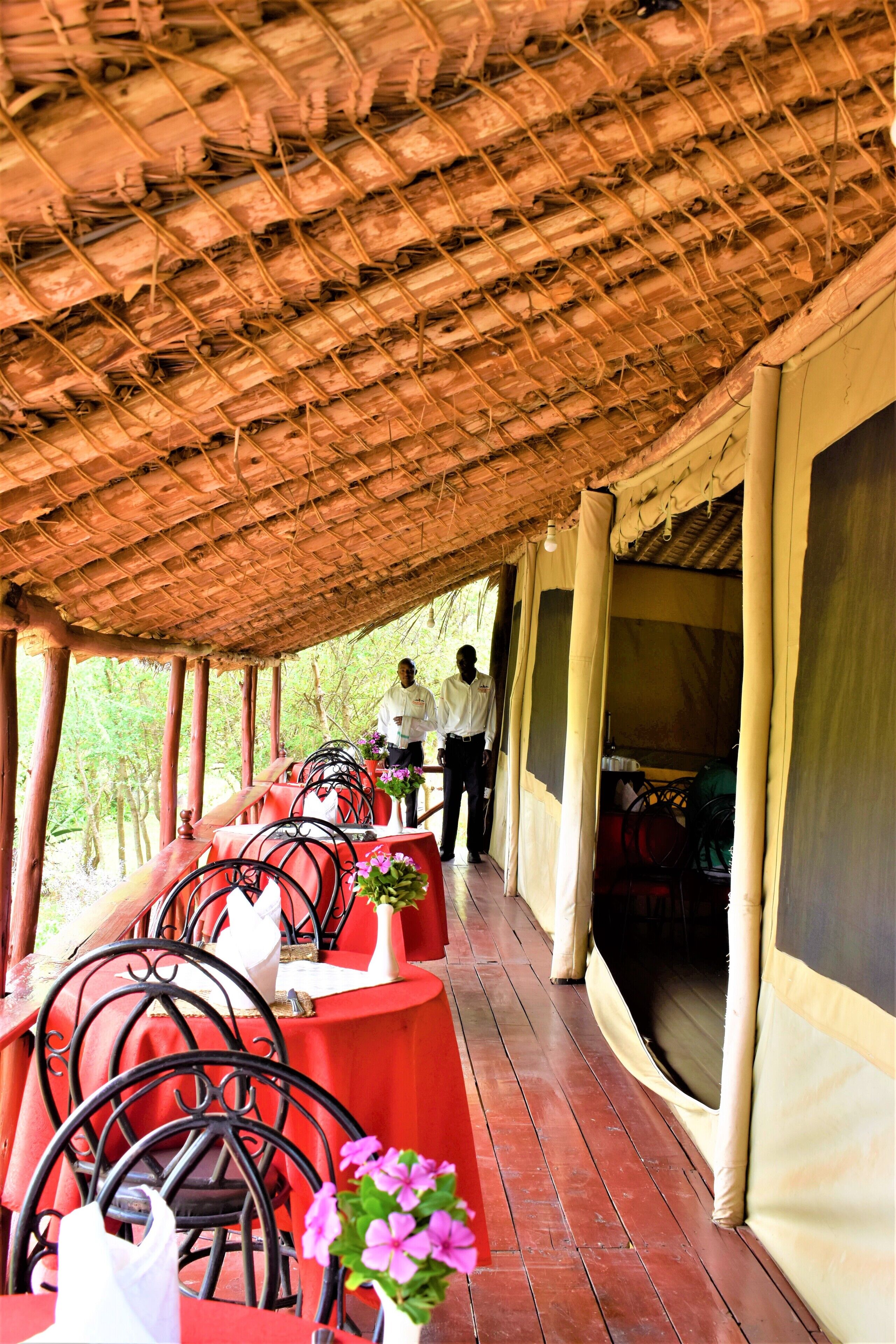 A covered outdoor seating area with tables and chairs, a person walking, and a tent-like structure.