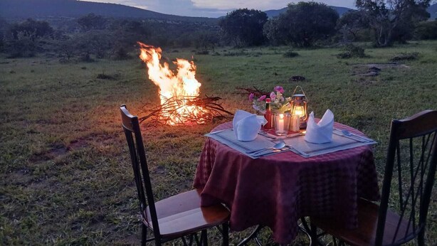 A table set outdoors with a fire in the background.
