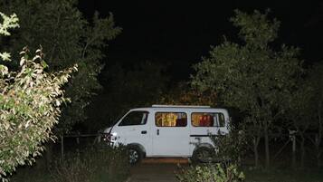 Een witte bus geparkeerd in een bebost gebied in de nacht.