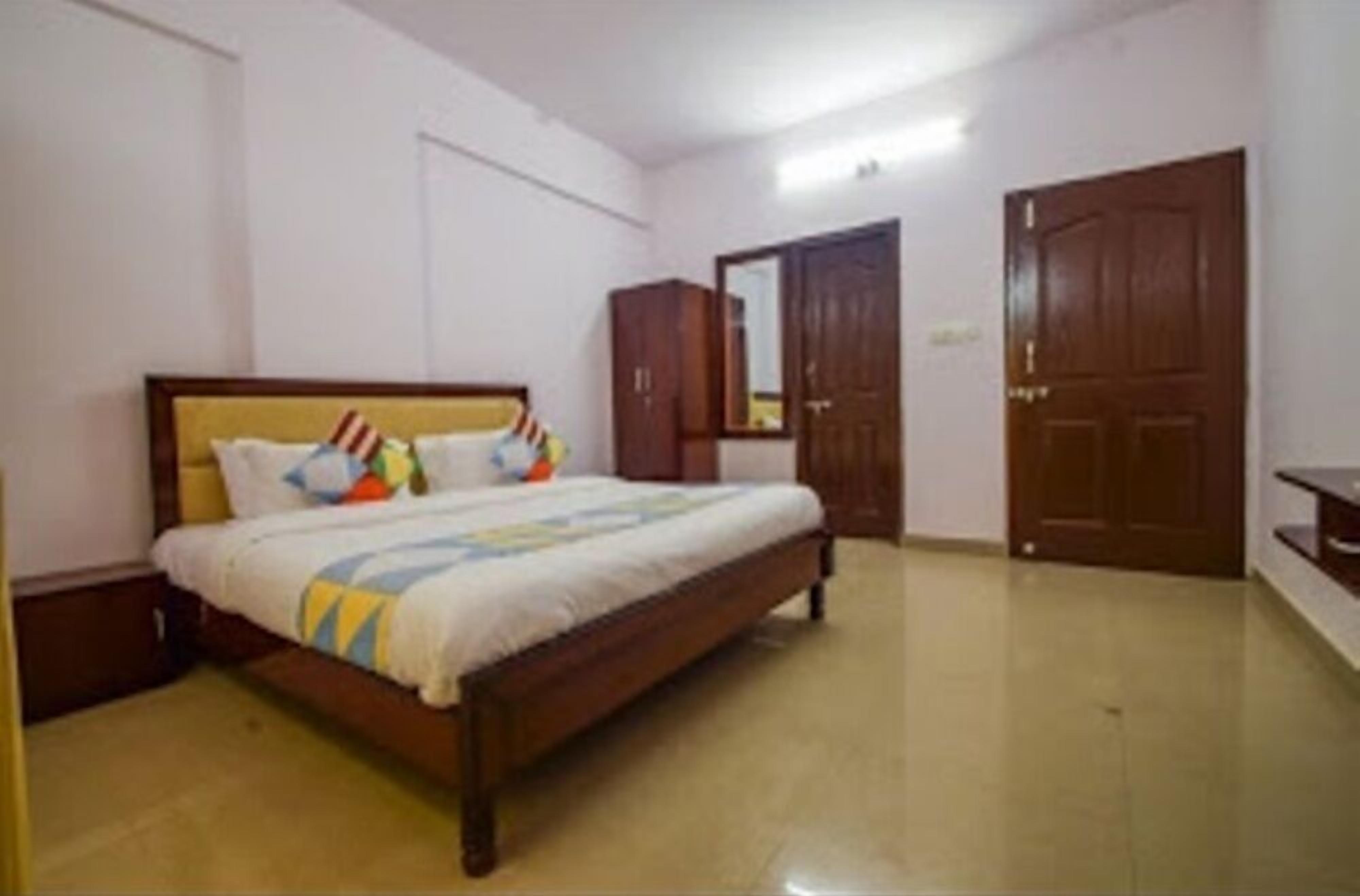 Un dormitorio con una cama de madera, un armario, un espejo y una puerta.