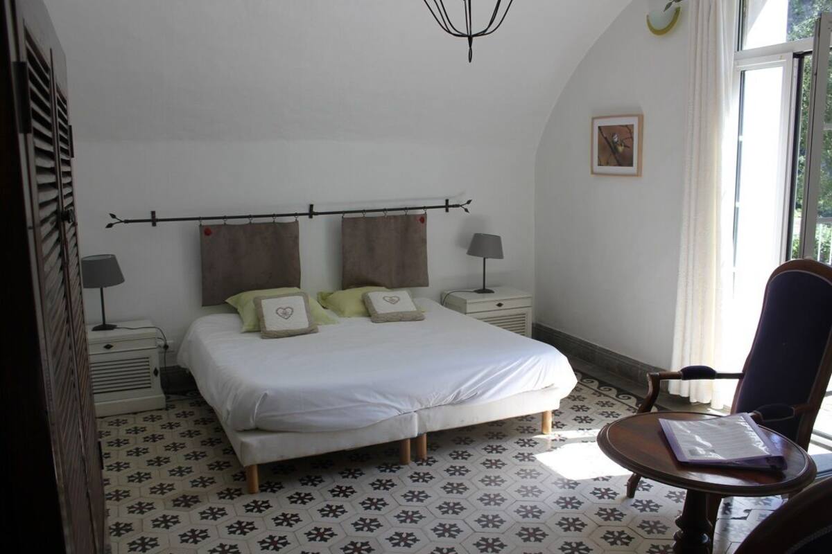 Een slaapkamer met een bed, nachtkastjes, een stoel en een raam.