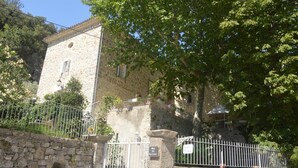 A stone building with a gate, surrounded by greenery and a stone wall. - Domaine de la Carrière (Sumene)