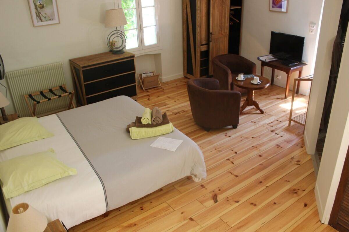 Een slaapkamer met een bed, een bureau, een stoel, een televisie en een raam.