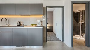 Une cuisine moderne avec des meubles gris, un évier en acier inoxydable et une machine à café.