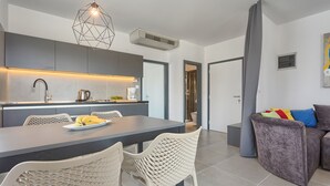 Une cuisine moderne avec un coin repas, des meubles de couleur grise et un canapé gris agrémenté de coussins colorés.