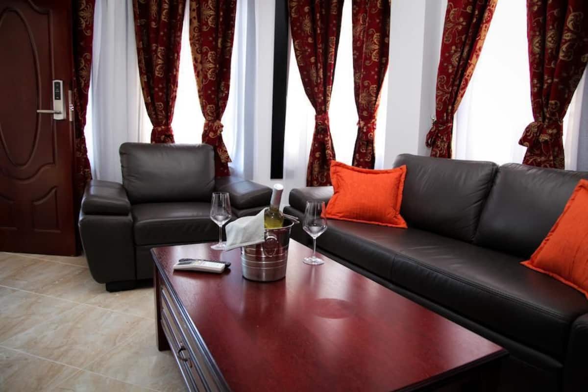 A modern living room with a black leather sofa, a wooden coffee table, and a remote control.