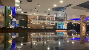 Un área de bar moderna con piso reflectante, diversas botellas de licor y copas en estantes.