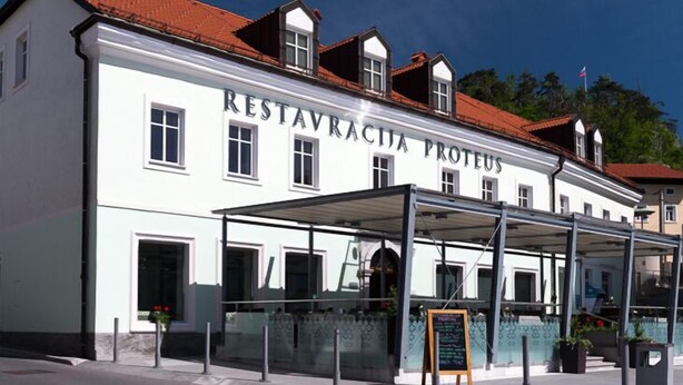 A building with a sign reading "Restavratia Proteus." - Postojna Cave Rooms & Apartments Proteus (Postojna)