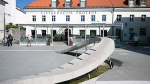 A building with a sign reading "Restavricja Proteus" and a curved pathway leading to the entrance. - Postojna Cave Rooms & Apartments Proteus (Postojna)