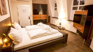 Une chambre d’hôtel avec un lit, des lampes de chevet, une télévision et une armoire.