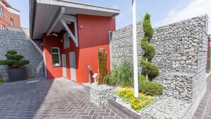 Un bâtiment rouge avec un mur en pierre et un chemin pavé de briques qui y mène.