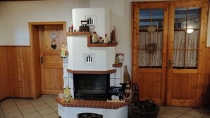 A cozy room with a fireplace, wooden walls, a door with a sign, and a window with curtains. - Gasthaus Wagner (Golzow)