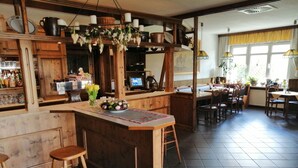 A restaurant with a wooden bar area, bar stools, and a dining area with tables and chairs. - Gasthaus Wagner (Golzow)