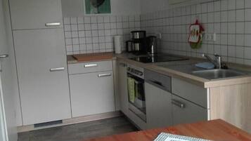 A compact kitchen with white cabinets, a stove, a sink, and a small countertop.