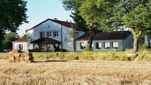 A two-story building with a porch, surrounded by a field of hay bales. - Gasthaus Wagner (Golzow)