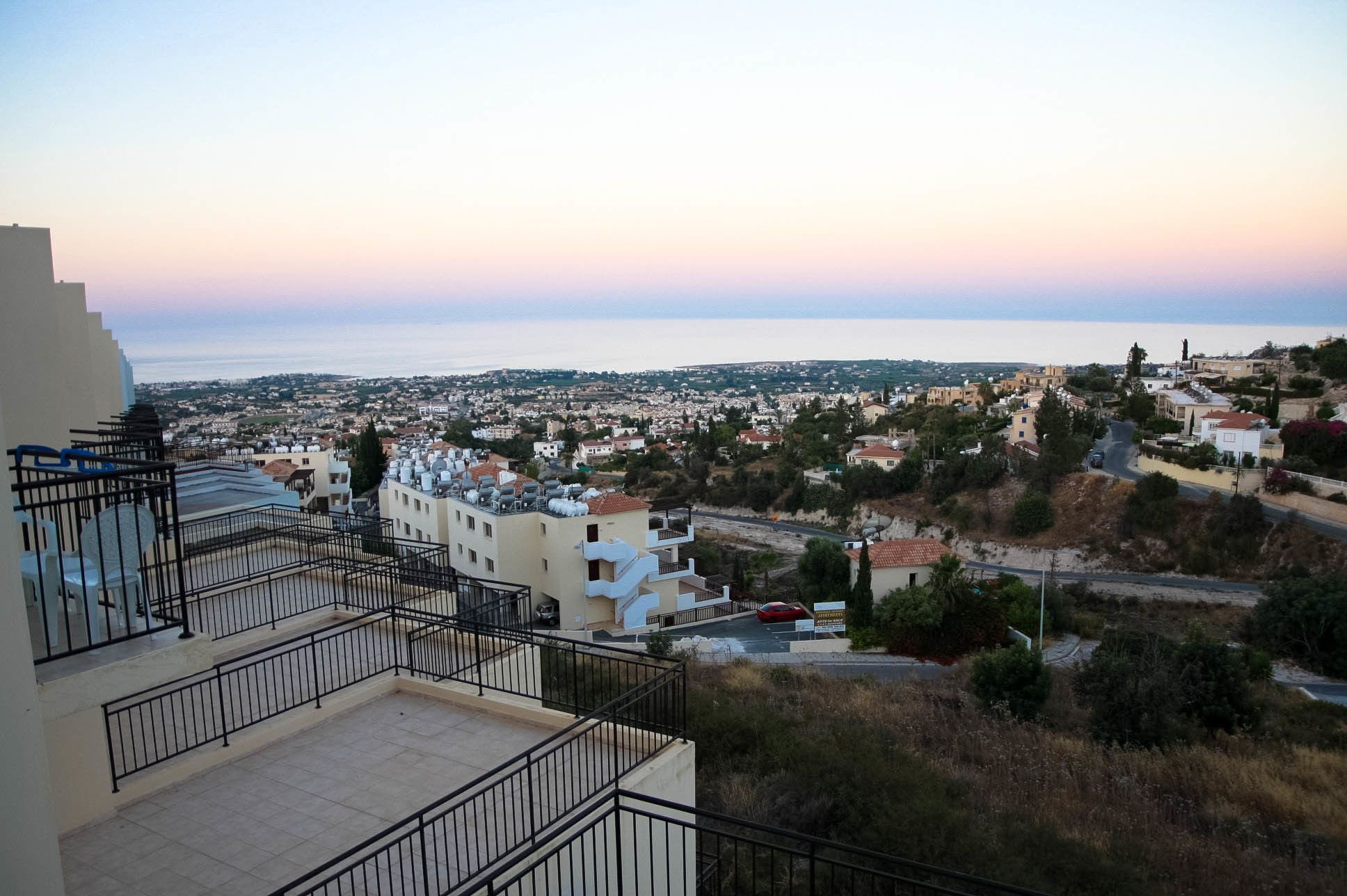 Zona residencial con vista al mar, con edificios de techos planos y un balcón con barandilla de metal.