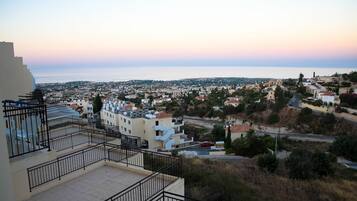 Zona residencial con vista al mar, con edificios de techos planos y un balcón con barandilla de metal.