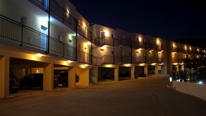 Un hotel de varios pisos con estacionamiento exterior y balcones.