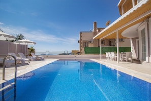Una piscina al aire libre, sombrillas, sillones reclinables de piscina