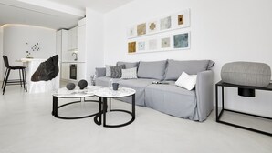 Ein modernes Wohnzimmer mit einem grauen Sofa, zwei runden Couchtischen und einem schwarzen Beistelltisch.