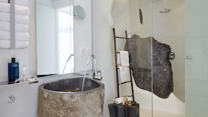 Ein modernes Badezimmer mit einem großzügigen Becken aus Stein, einer Duschkabine aus Glas und einem großen Spiegel.