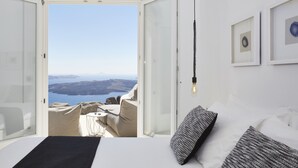 Ein Schlafzimmer mit einem großen Bett, Meerblick und einem Balkon mit Sitzgelegenheit.