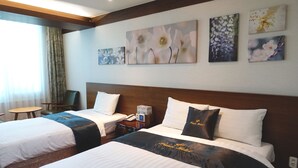 A hotel room with two beds, a nightstand, a chair, and artwork on the wall. - Prince Hotel (Goseong)