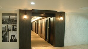 A hallway with a patterned wall, a tiled floor, and a series of doors. - Prince Hotel (Goseong)