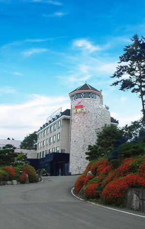 Un hotel con una torre de piedra y un letrero en un idioma extranjero.