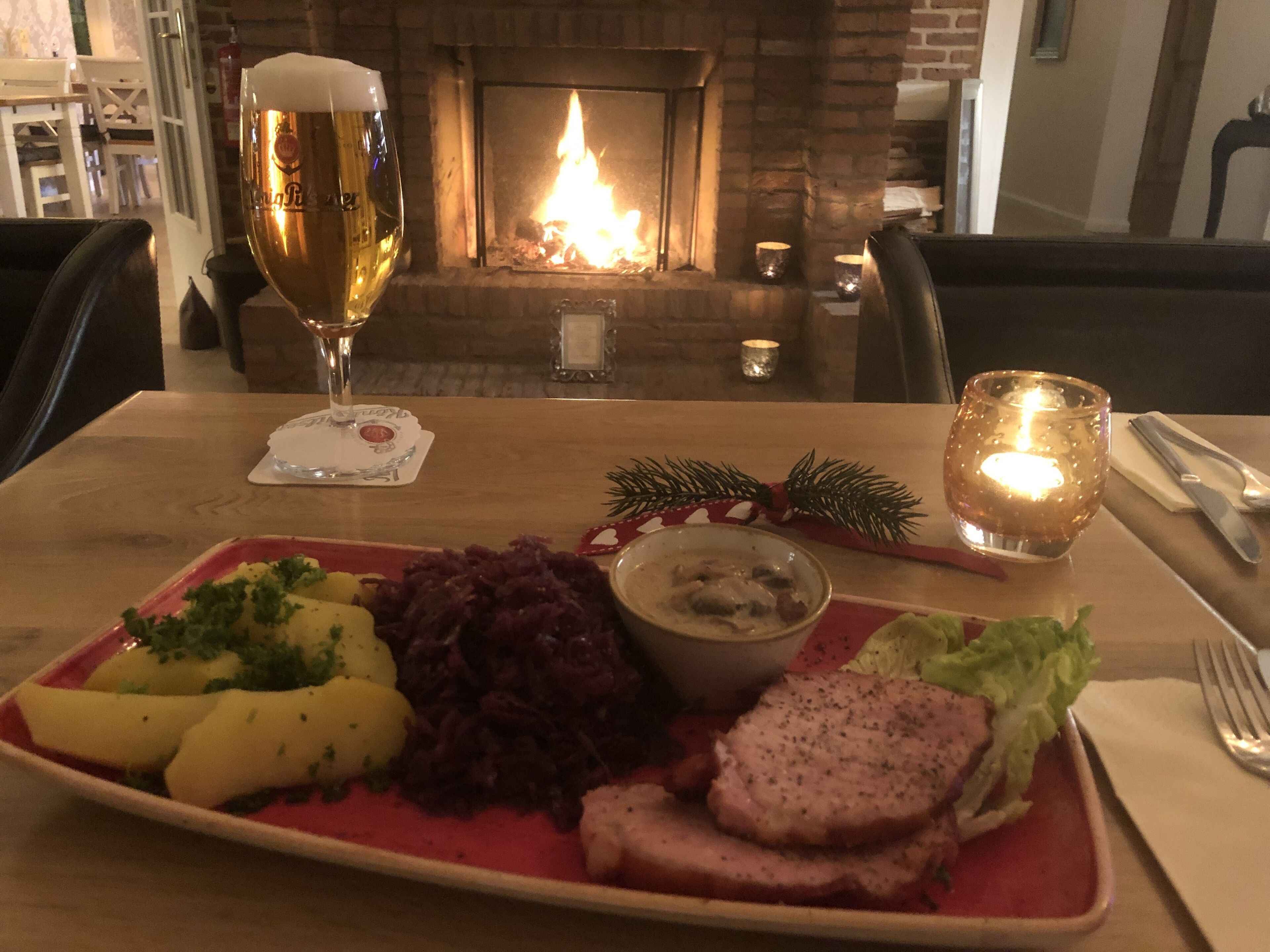 Una mesa de comedor con un plato de comida, una jarra de cerveza y una vela.