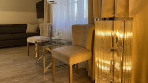 A modern living room with a glass coffee table, two armchairs, a sofa, and a decorative lamp. - Hotel Petersen‘s Landhaus Scharbeutz (Scharbeutz)