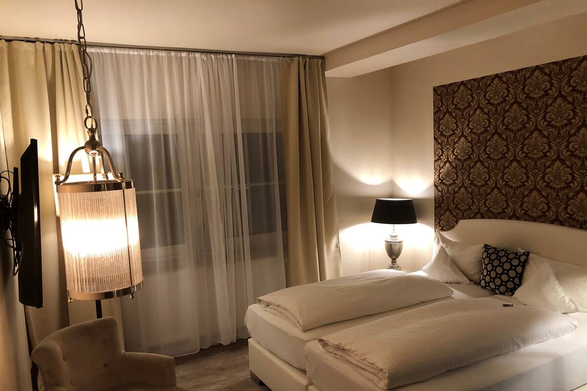 A hotel room with a bed, a chair, a lamp, and a wall with a patterned design.