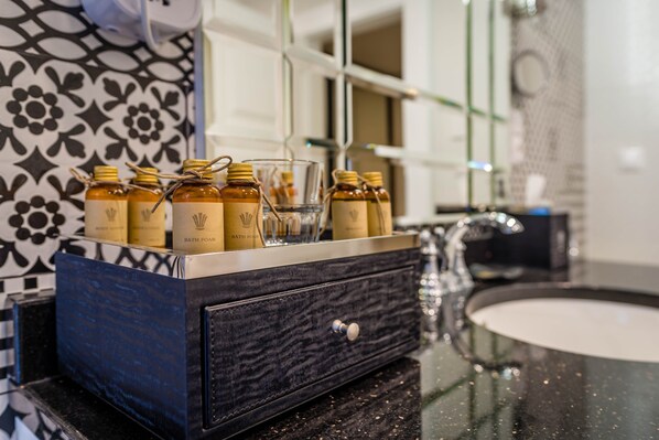 A bathroom vanity with a black marble countertop, a glass sink, and a decorative mirror.